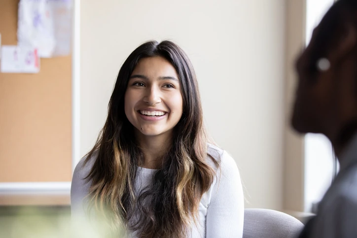 Estudante jovem e feliz participando de uma reunião colaborativa em ambiente de aprendizado ou profissional