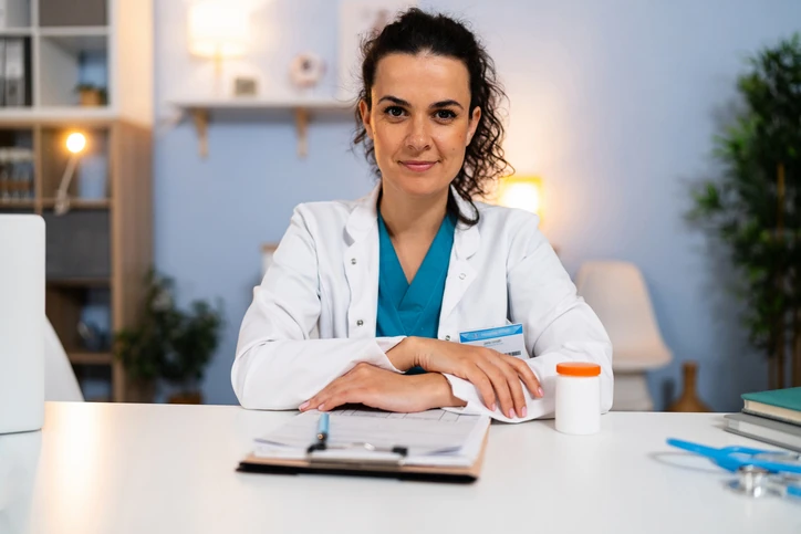 Médica profissional atendendo em seu consultório médico com equipamentos de saúde e prontuário para consulta