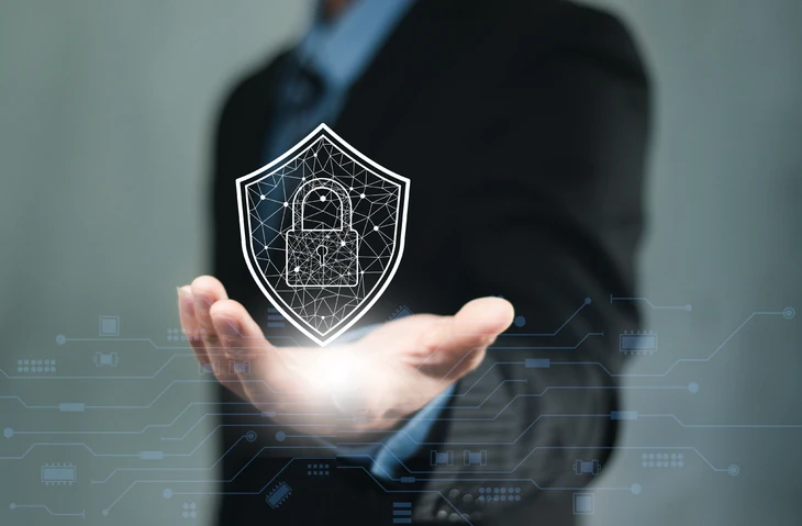 Executivo segurando ícone digital de escudo e cadeado representando segurança cibernética