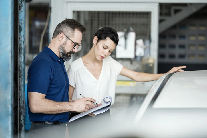 Mecânico e cliente revisando orçamento de reparo automotivo em uma oficina