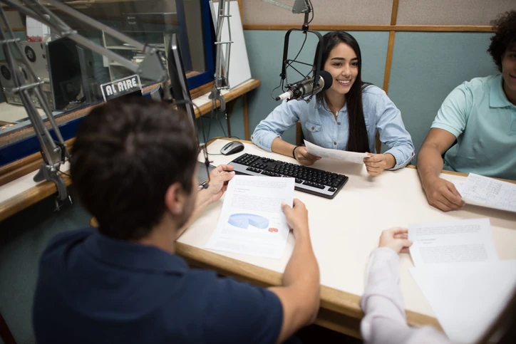 Estudantes universitários participando de um programa de rádio em estúdio