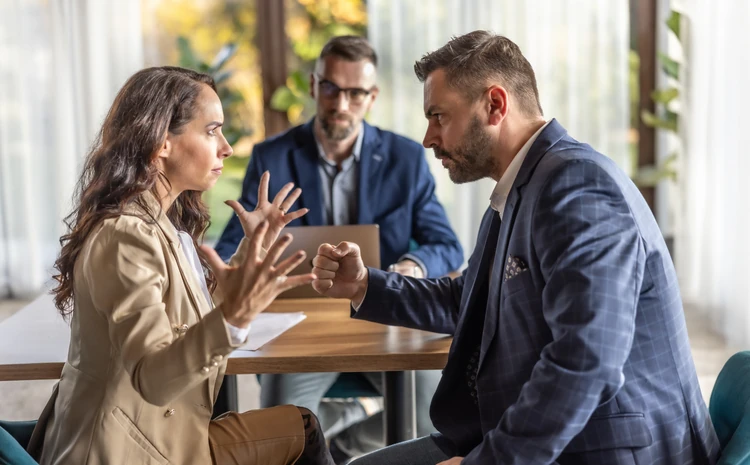 https://estaticos.animaeducacao.com.br/medias/20260401174250/GettyImages-2116642885.webp Homem e mulher discutindo agressivamente em uma reunião de negócios no escritório