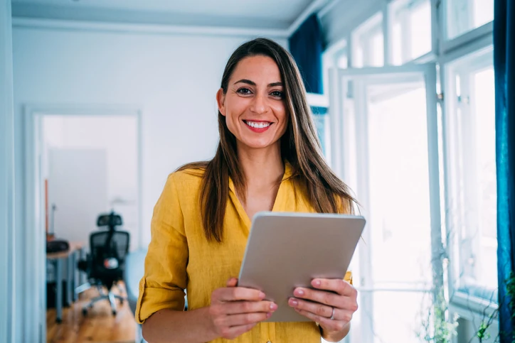 Profissional sorridente utilizando tablet digital para trabalho e produtividade no ambiente corporativo