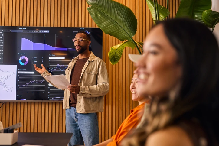 Equipe de marketing analisando gráficos de desempenho e ROI em uma apresentação de negócios moderna