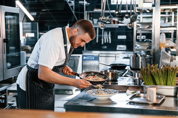 Chef de cozinha profissional preparando um prato requintado em um ambiente de cozinha industrial moderna e equipada