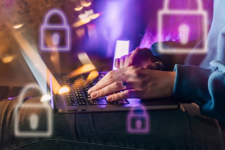Pessoa digitando em um notebook com ícones digitais de cadeados de segurança cibernética