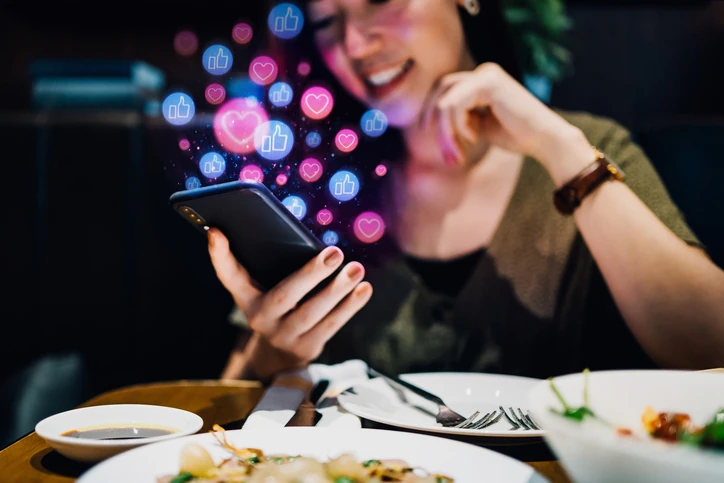 Interação digital nas redes sociais: jovem engajando com conteúdo online através do smartphone em um restaurante