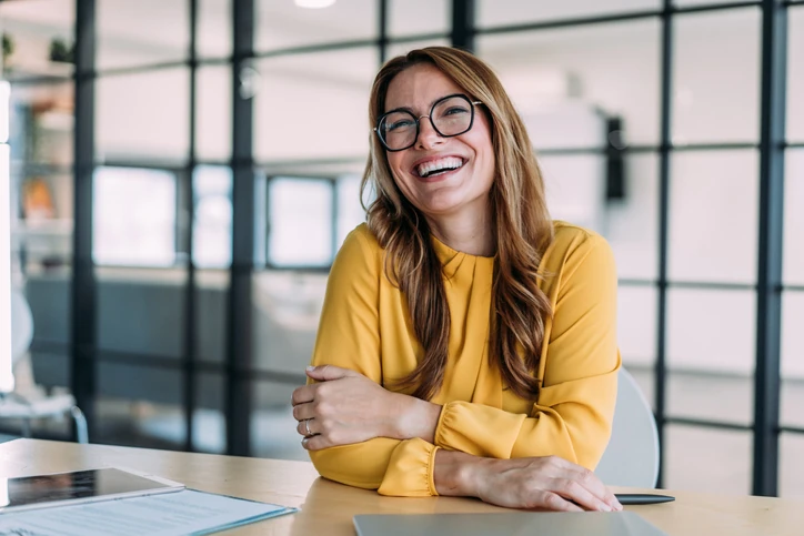 Profissional de sucesso sorrindo em ambiente corporativo moderno com foco em bem-estar e produtividade no trabalho