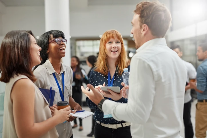 Profissionais diversos interagindo e fazendo networking em ambiente de conferência corporativa para desenvolvimento de carreira Grupo de profissionais diversos conversando e sorrindo durante um evento corporativo ou conferência de negócios