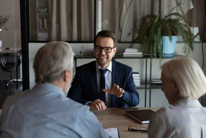 Consultor financeiro sorridente em reunião com casal de idosos em escritório