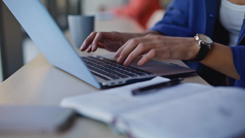 Estudante ou profissional focada trabalhando e digitando em um laptop em um ambiente de escritório ou biblioteca