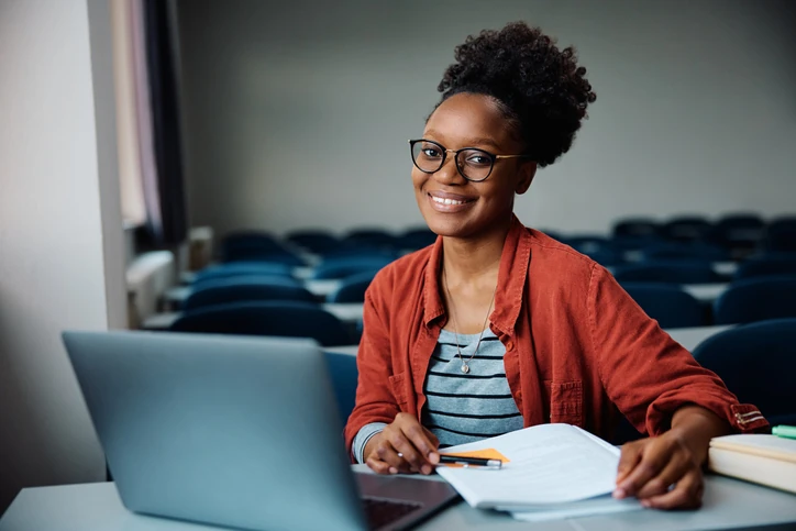 Estudante universitária focada estudando com notebook em sala de aula acadêmica para sucesso acadêmico