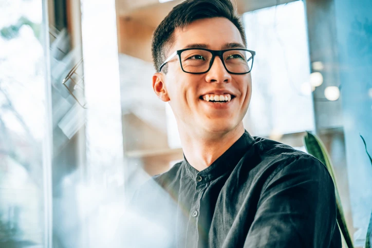 Jovem profissional talentoso e motivado sorrindo enquanto trabalha em um ambiente de escritório moderno e iluminado