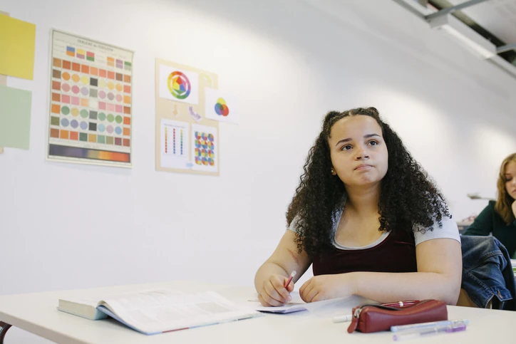 Estudante atenta em sala de aula de design com teoria das cores na parede