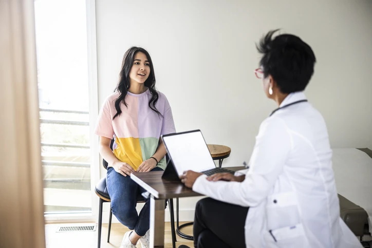 Paciente jovem em consulta médica conversando com médica em consultório