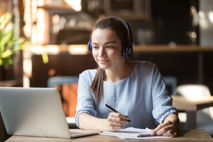 Estudante jovem usando fones de ouvido e notebook para aula online ou curso EAD.