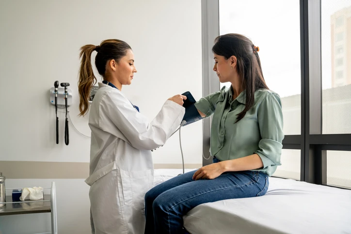 Consulta médica profissional com foco no monitoramento da saúde e aferição de pressão arterial em ambiente clínico especializado Médica aferindo a pressão arterial de uma paciente em consultório clínico