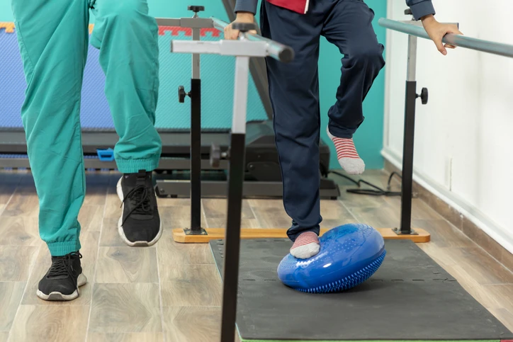 Sessão de fisioterapia focada em reabilitação motora e treino de equilíbrio com uso de disco proprioceptivo em clínica especializada