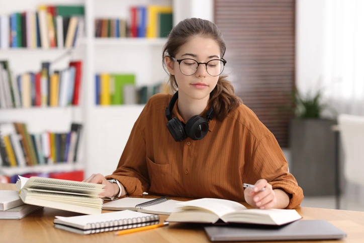 Estudante universitária concentrada nos estudos em uma biblioteca organizada para promover o aprendizado