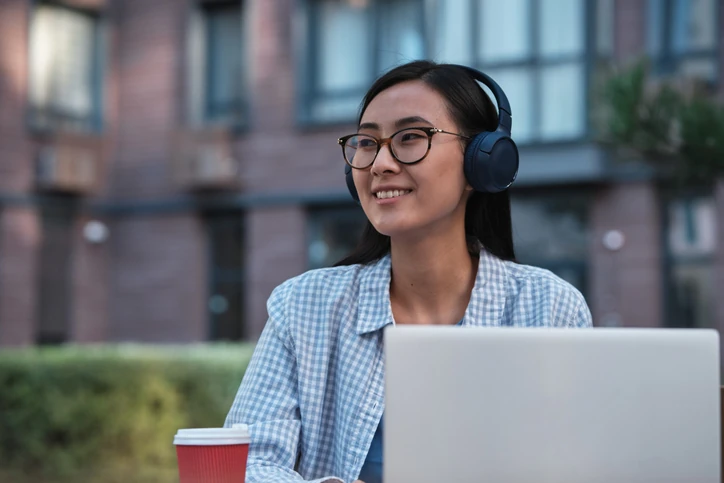 Estudante jovem usando fones de ouvido e notebook em ambiente externo