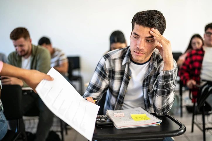 Estudante universitário preocupado recebendo uma prova em sala de aula