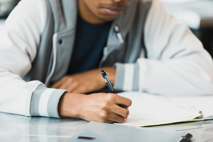 Estudante jovem escrevendo em um caderno em sala de aula