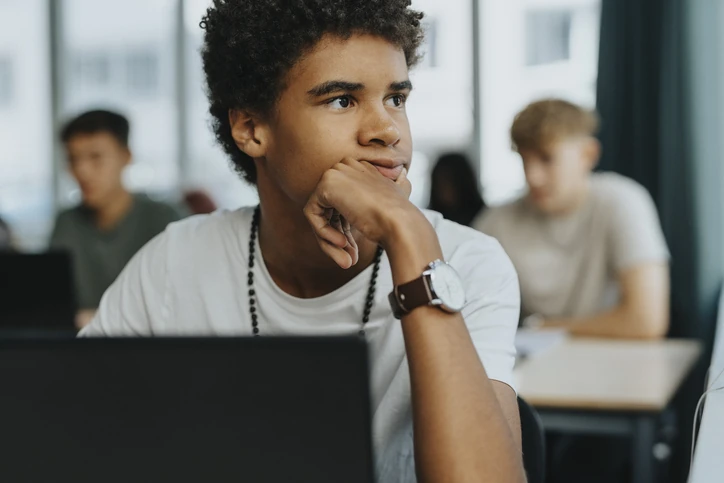 Estudante jovem pensativo usando computador em sala de aula