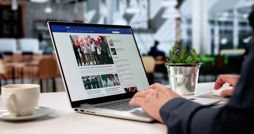 Pessoa trabalhando em um computador portátil em um ambiente corporativo lendo portais de notícias e acompanhando atualizações diárias