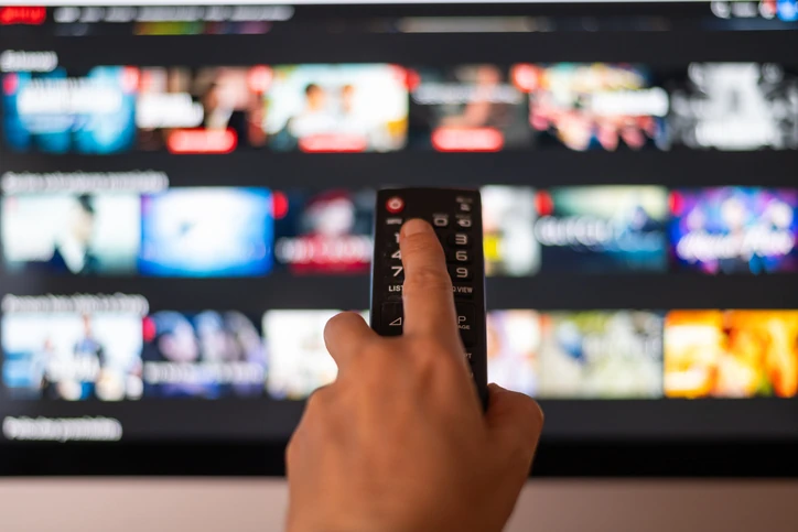 Pessoa escolhendo filmes e séries em uma plataforma de streaming usando o controle remoto da televisão