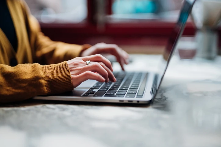 Pessoa trabalhando remotamente digitando em um computador notebook para realizar tarefas acadêmicas ou profissionais no dia a dia