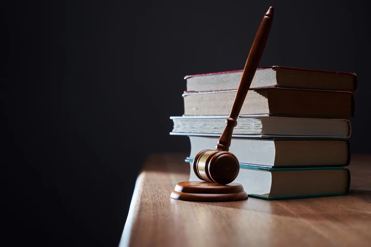 Martelo de juiz e livros de direito representando justiça, advocacia e estudos jurídicos Martelo de juiz sobre uma pilha de livros jurídicos em uma mesa de madeira