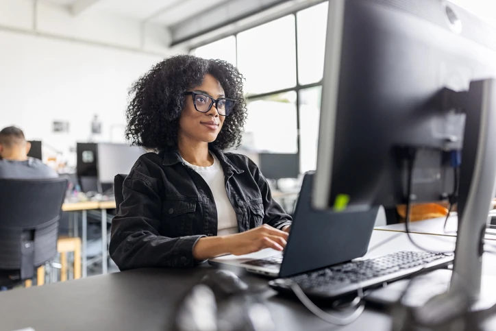 Profissional focada utilizando computador em ambiente de escritório colaborativo e moderno para aumentar a produtividade no trabalho