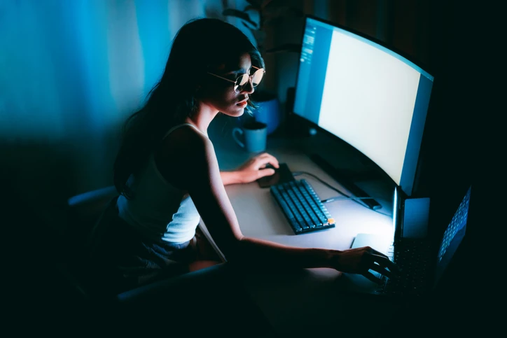Mulher jovem trabalhando em um computador no escritório escuro