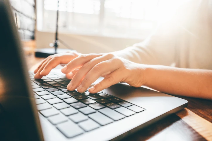 Pessoa utilizando um laptop para trabalho ou estudos em ambiente com luz natural produtiva