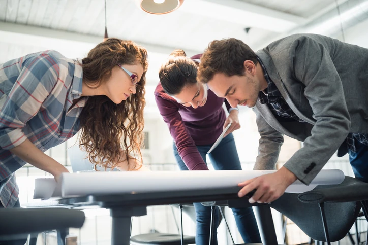 Equipe colaborativa trabalhando em projetos arquitetônicos e estratégicos em um ambiente corporativo inovador