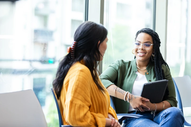 Duas mulheres conversando em um ambiente de escritório moderno com iluminação natural