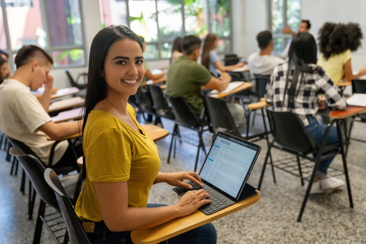 Estudante universitária focada em seus estudos usando tecnologia em sala de aula para acompanhar as atividades acadêmicas