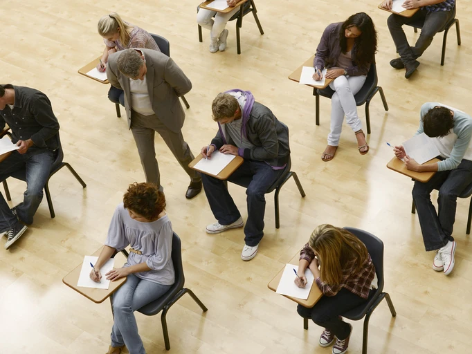Professor monitorando estudantes focados em uma avaliação acadêmica importante em ambiente universitário