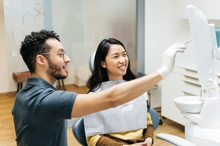 Dentista explicando o tratamento odontológico para a paciente usando imagens digitais no consultório