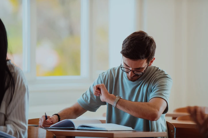 Jovem estudante resolvendo questões do ENEM com expressão de foco, controlando o tempo de prova.
