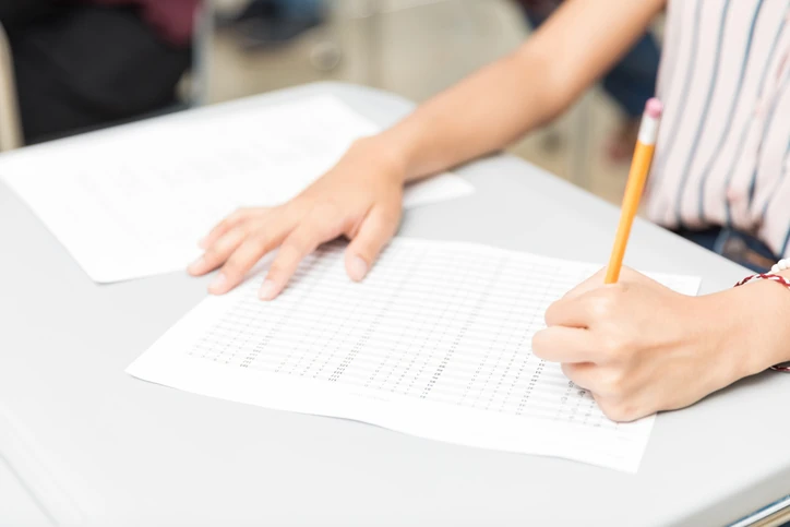 Estudante preenchendo cartão de respostas de prova com lápis durante exame