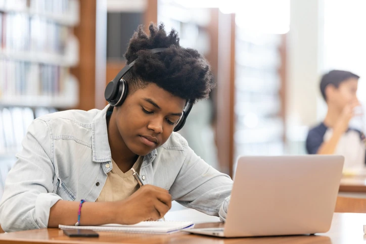 Estudante escrevendo a redação do Enem. Jovem estudante enquanto faz anotações em um caderno, preparando-se para a redação do Enem.
