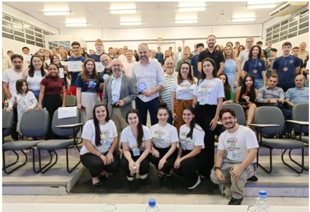 Grupo de estudantes e professores em cerimônia de premiação acadêmica