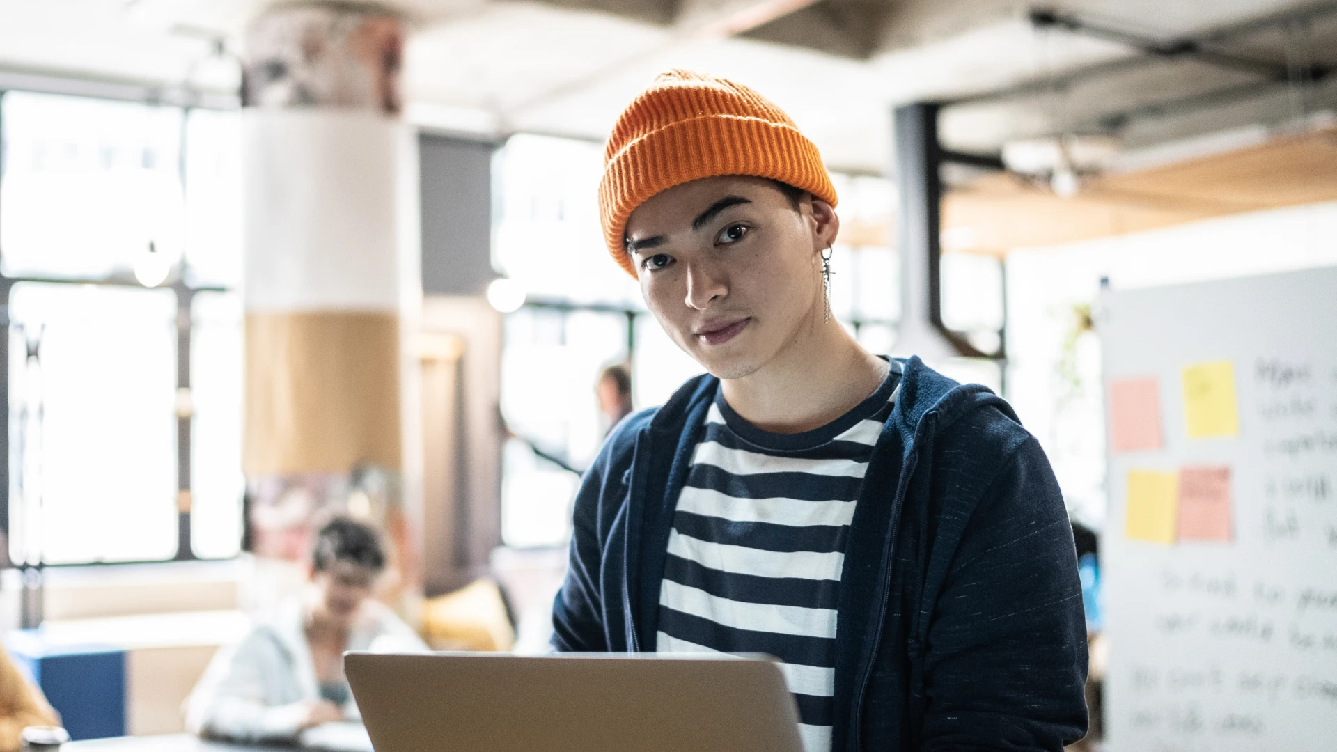Estudante ou profissional jovem utilizando notebook em um ambiente de co-working moderno e criativo para estudo ou trabalho
