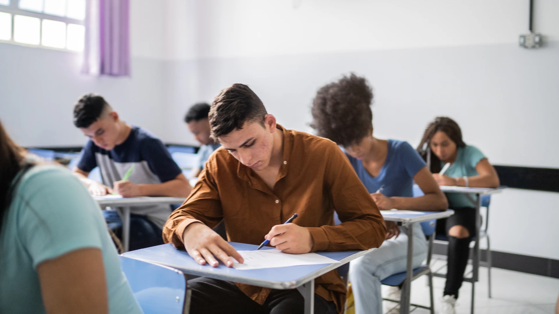 Estudantes concentrados realizando uma prova em uma sala de aula