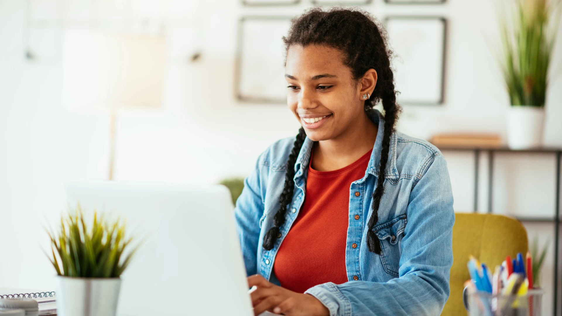 Estudante jovem e sorridente usando notebook em um ambiente de estudo ou trabalho