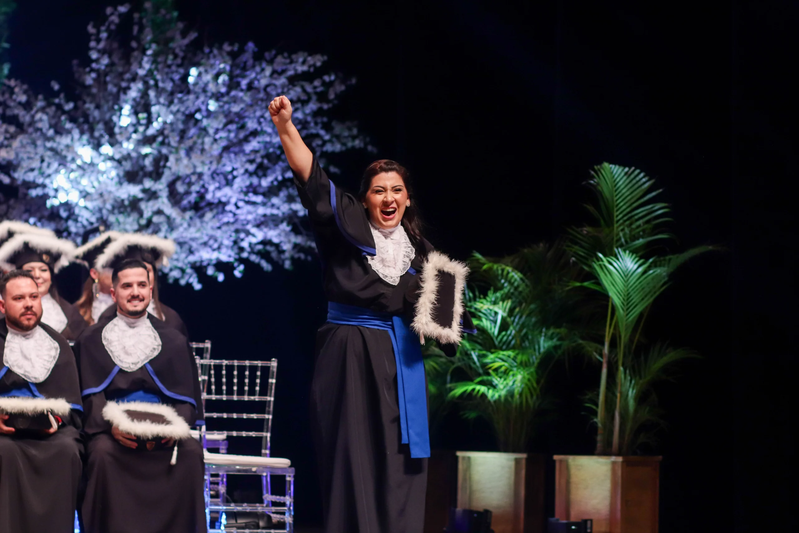 Formanda universitária celebra a conquista da graduação durante a cerimônia oficial de colação de grau no palco