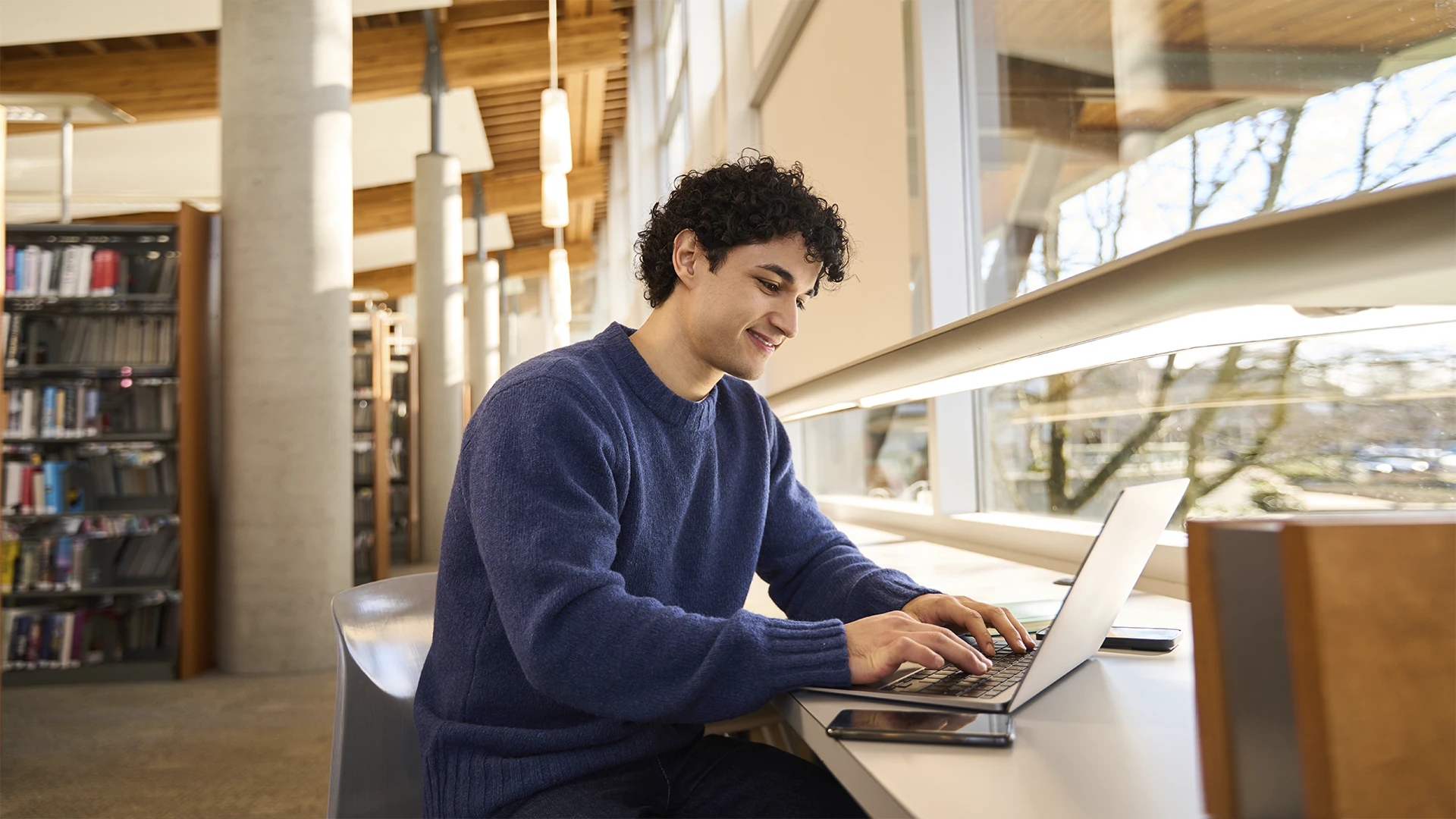 Estudante universitário usando laptop em uma biblioteca moderna