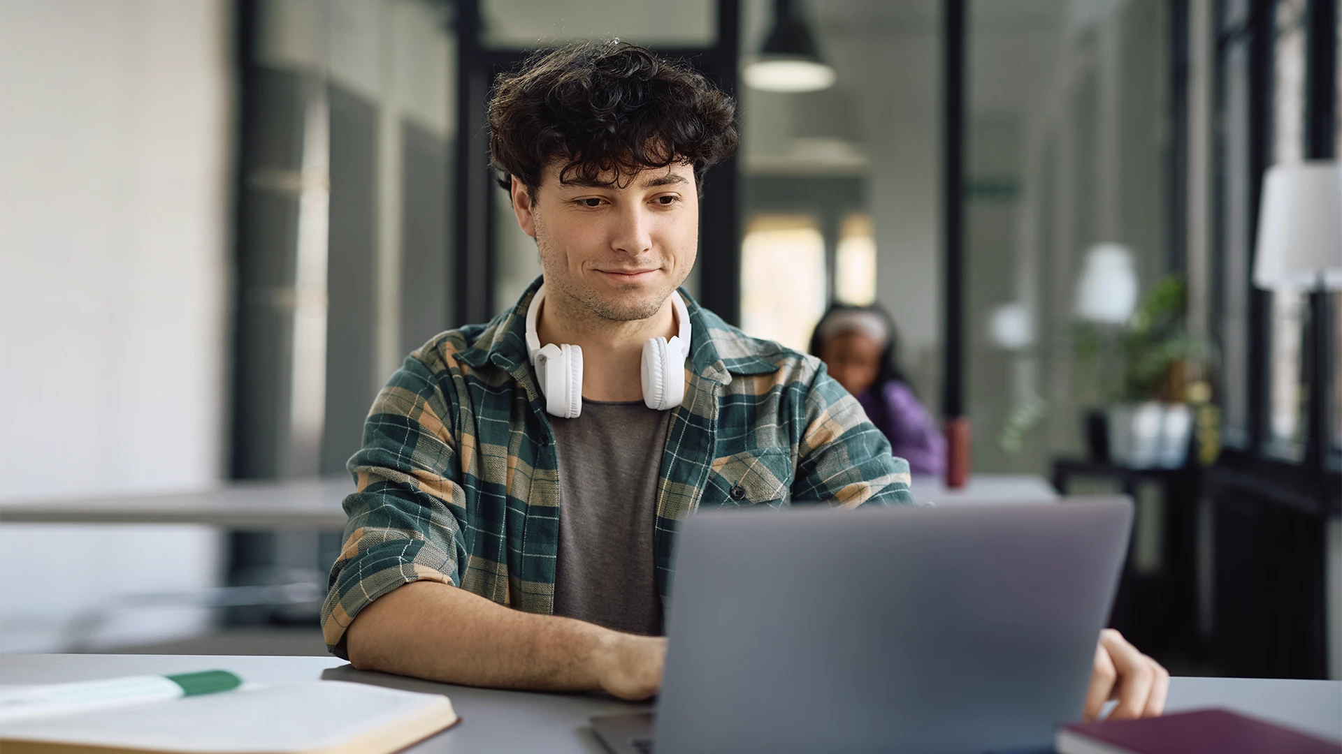 Jovem estudante universitário usando notebook em ambiente de biblioteca moderna