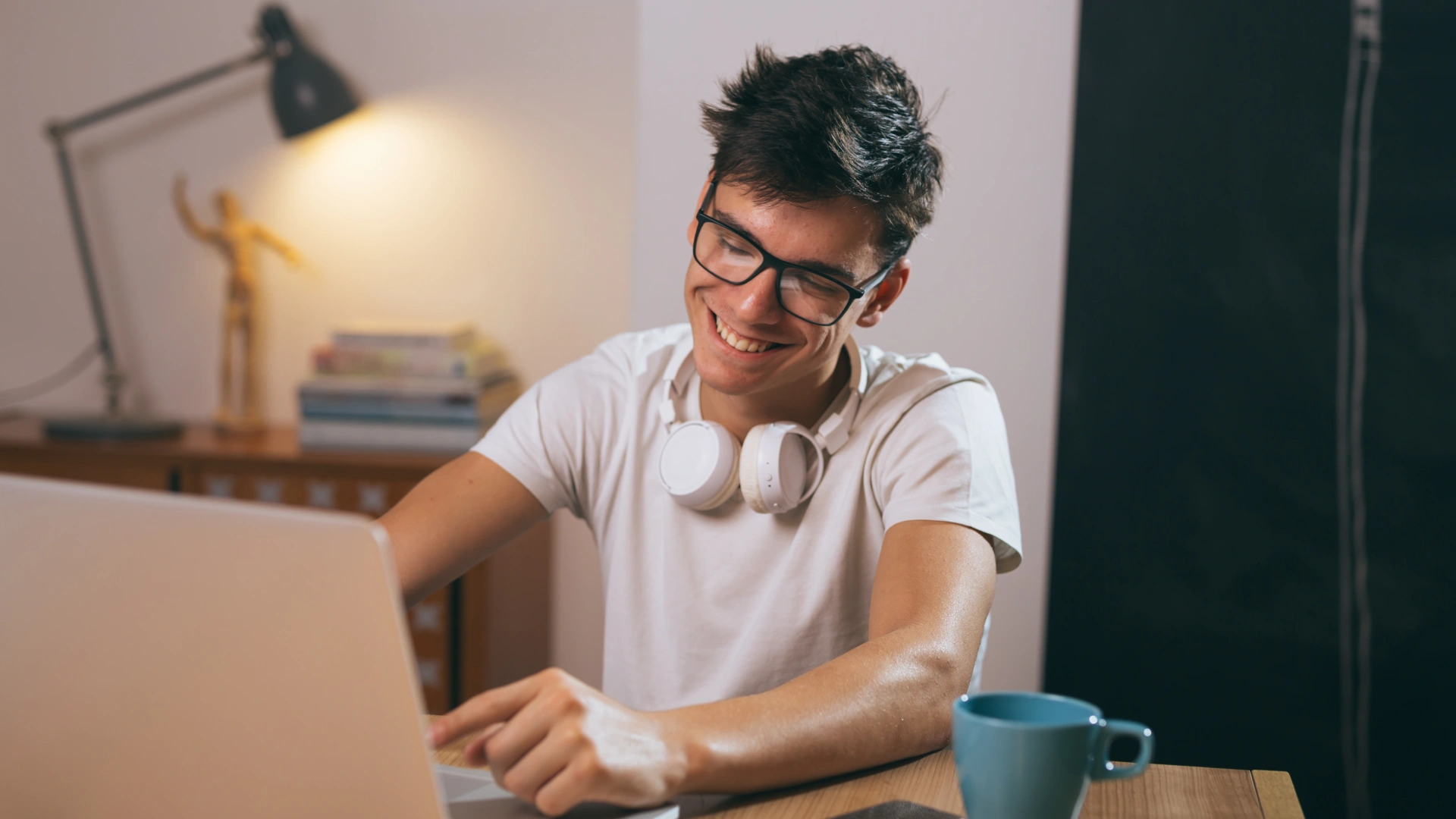 Jovem estudante sorridente usando laptop e fones de ouvido em um ambiente de estudo confortável